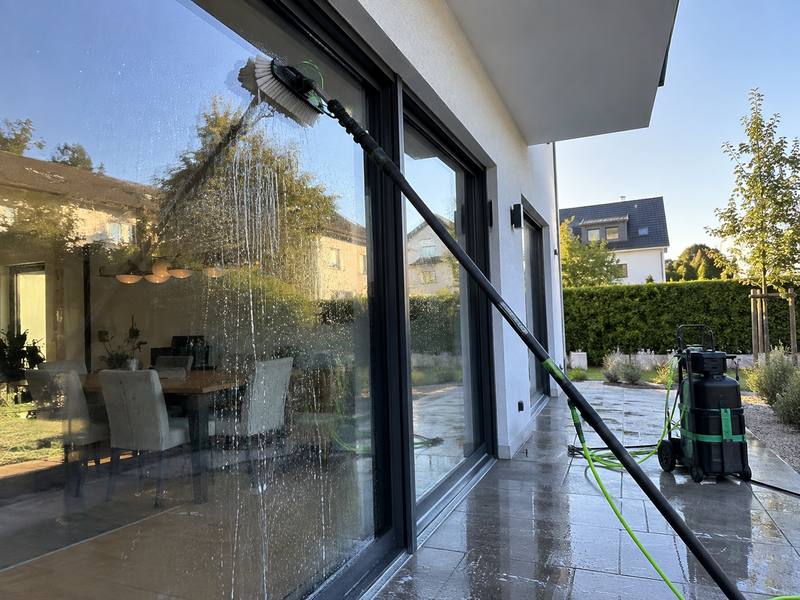 Glasfront wird mit Bürste und Wasser gereinigt