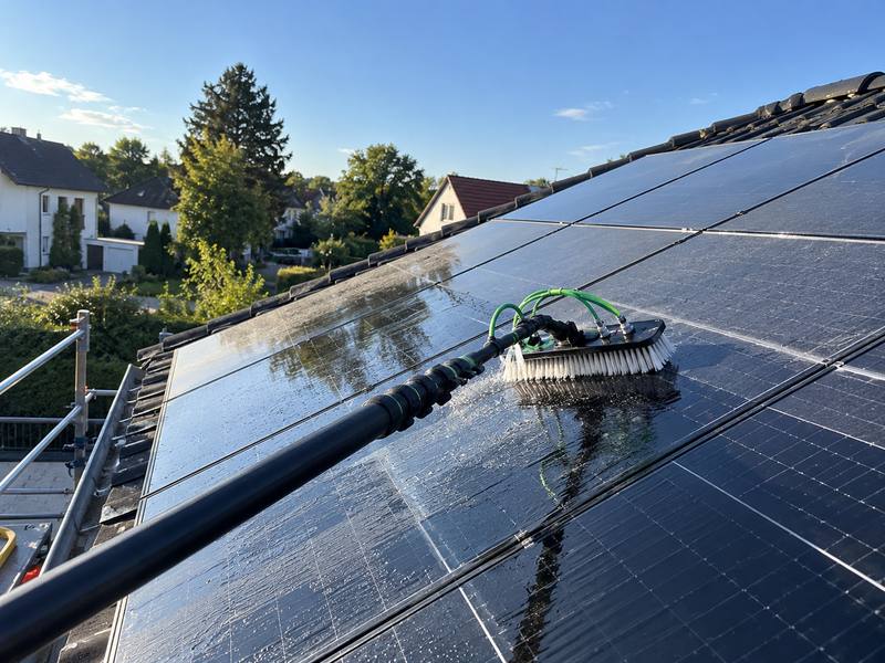 Solarmodule auf einem Hausdach werden mit einer Bürste gereinigt